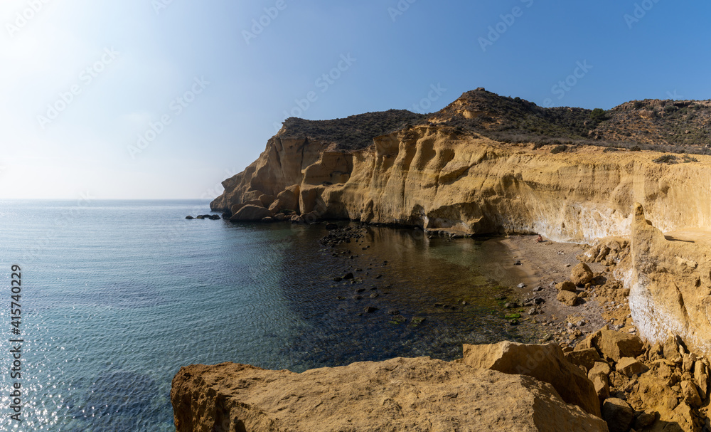 calm idyllic ocean water in the Mediterranean with yellow sandstone cliffs behind