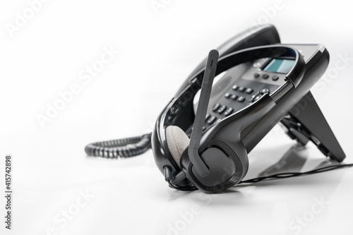 Quadro su tela Office light background VOIP headset headphones telephone on office desk concept