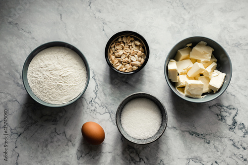 Ingredients for baking cookies. Flour, sugar, vanilla, salt, butter, peanut, egg. Top view horizontal photo, marble backdrop