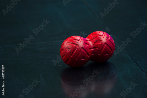 Red receiving ball massage on black parquet. Sport massage concept photo