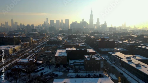 aerial drone establishing shot footage of Chicago downtown area during the winter time early in the morning after sunrise.  the white snow covers most of the city architecture landscape.   