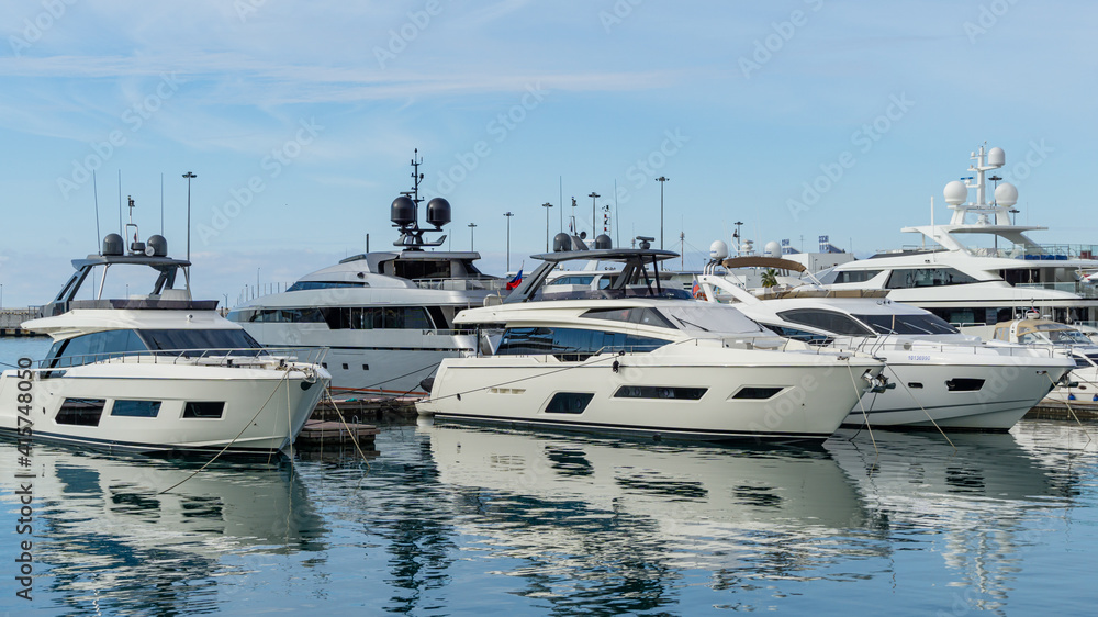Ships, yachts and boats on blue surface of Black Sea by pier of Commercial seaport of Sochi. Resort city center. Sochi, Russia - November 23, 2020 Ships, yachts and boats on blue surface of Black Sea by pier of Commercial seaport of Sochi. Resort city center. Sochi, Russia - November 23, 2020