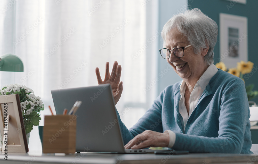 Senior woman having a video call at home - obrazy, fototapety, plakaty 
