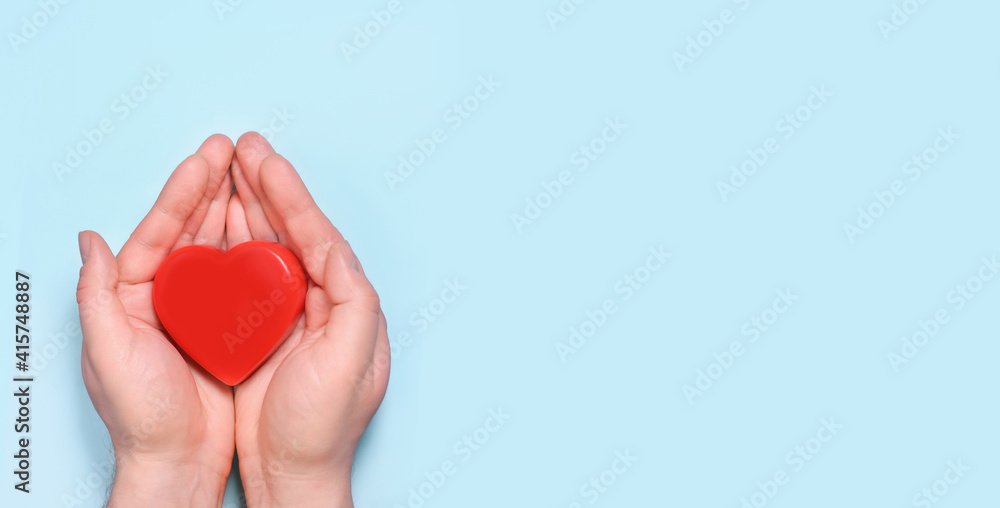 Obraz premium Red heart in man's hands isolated on blue background. Healthcare and hospital medical concept. Symbolic of Valentine day.Top view with space for text. Banner