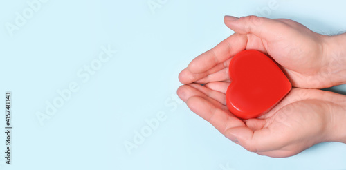Red heart in man's hands isolated on blue background. Healthcare and hospital medical concept. Symbolic of Valentine day.Top view with space for text. Banner