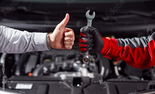 Anonymous man approving job of auto mechanic in workshop