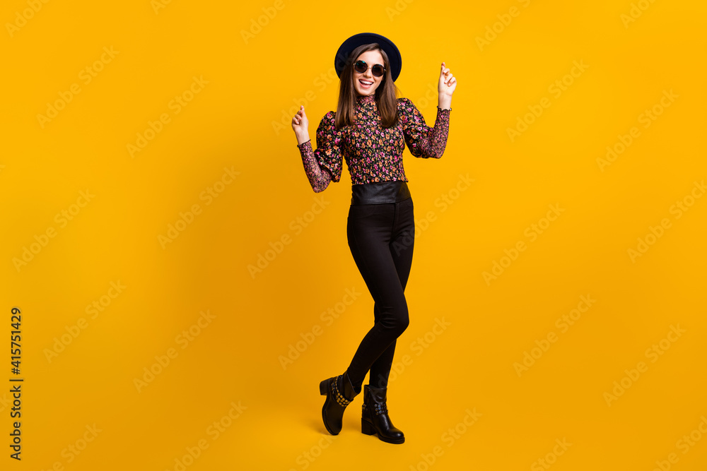 Obraz premium Full length body size photo of smiling female student dancing on floor clicking fingers in headwear isolated vibrant yellow color background