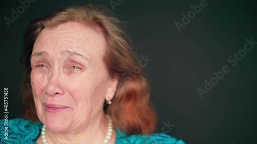 Slow motion view of happy old woman with red long hair who smiles happily and talks photo