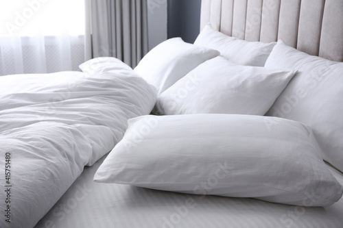 Comfortable bed with soft white pillows, closeup