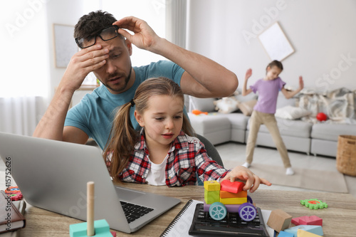 фотографія Children disturbing stressed man in living room