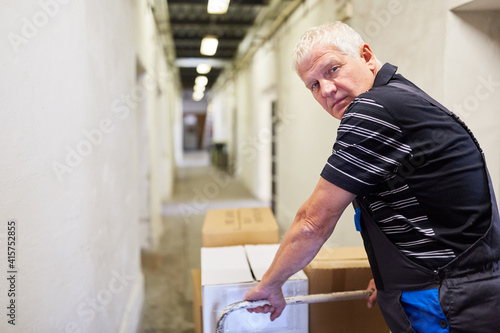 Older worker pushes packages onto push cart