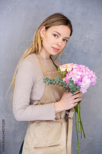 Young caucasian female florist collects a romantic bouquet of roses.