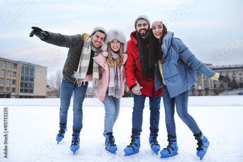 фотографія Happy friends at ice skating rink outdoors
