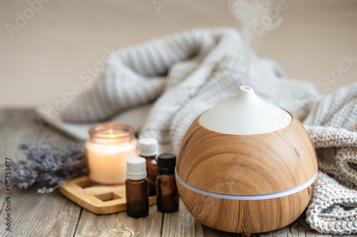 Cozy composition with an air humidifier, a set of aromatic oils and a candle.