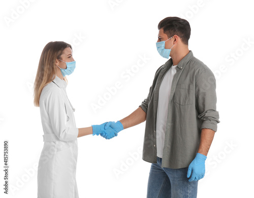 Doctor and patient in protective masks shaking hands on white background
