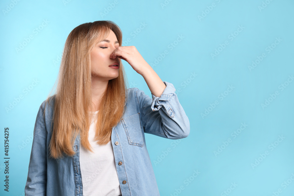Young woman suffering from runny nose on light blue background. Space for text Young woman suffering from runny nose on light blue background. Space for text