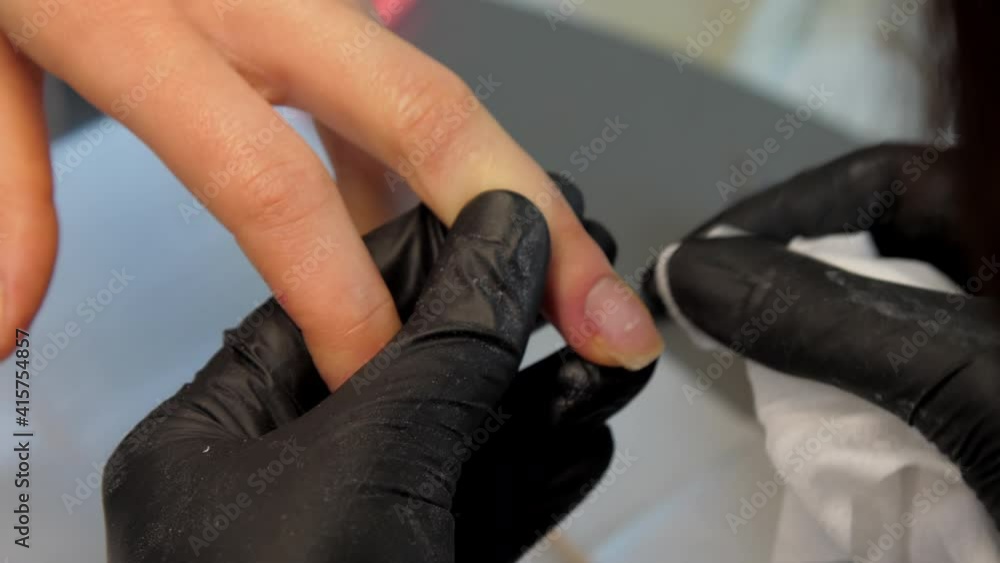 Beauty salon worker moves brown wooden orange sticks on lady fingernails and wipes with white napkin closeup. Concept fashion Beauty salon worker moves brown wooden orange sticks on lady fingernails and wipes with white napkin closeup. Concept fashion