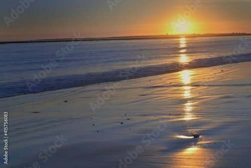 beautiful sunset reflecting on the sea and wet sand in atlantic ocean beach
