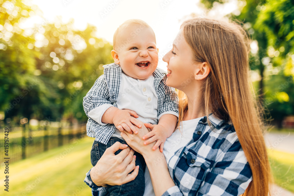 Fototapeta premium mother walking and hugging her baby in the park on a sunny day, Mother's Day,