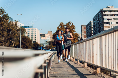 Group of sports people running in city street in morning. © Zoran Zeremski