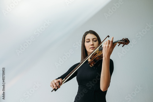 Violinist woman. Online education. Distance lesson. Lockdown reality. Inspired lady enjoying playing violin closed eyes with transparent plastic film under head isolated neutral copy space. photo