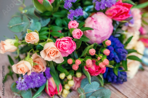 Close up view of a beautiful bouquet of mixed coloful flowers on wooden table.