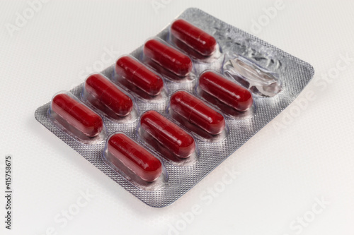 Slika na platnu Red capsules in started blister packing on light colored surface