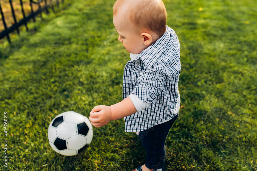 Happy little kid playing soccer ball in the park. Children are playing football Happy little kid playing soccer ball in the park. Children are playing football