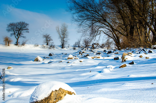 Snow covered bank of the river with big stones