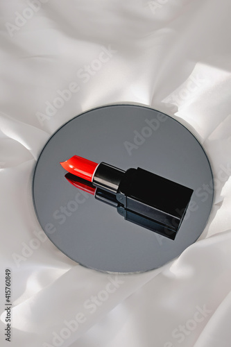 Red lipstick on a round mirror with reflection.