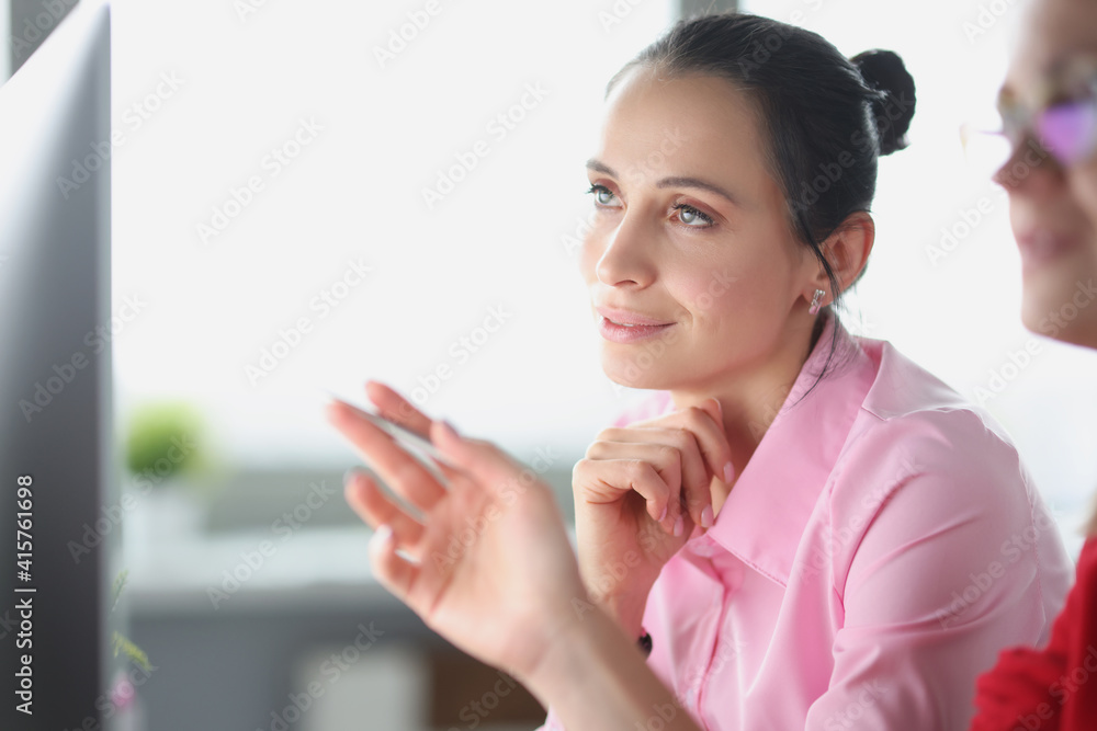 Two women looking at computer screen and communicate Two women looking at computer screen and communicate