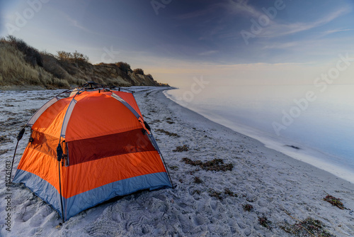 Fototapeta Naklejka Na Ścianę i Meble -  Orange tent on the Baltic sea coastline. Camp at the Baltic sea coast. Camping on the sea coastline.Shady beach shelter with UV protection on on sandy beach.