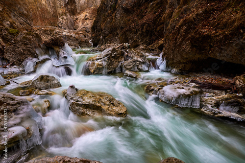 beautiful landscape with a mountain river with small waterfalls in winter day in the canyon.