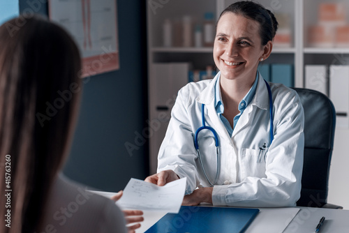 Foto Smiling doctor giving a prescription to a patient