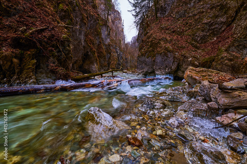 beautiful landscape with a mountain river with small waterfalls in winter day in the canyon.