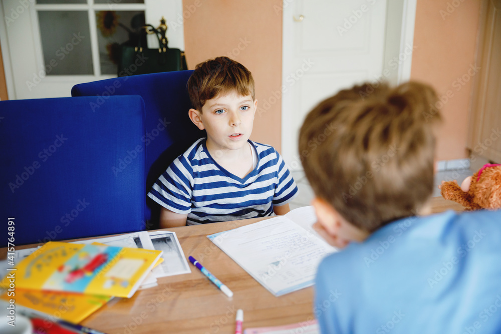 Two hard-working school kids boys making homework during quarantine time from corona pandemic disease. Children, brothers writing with pen, staying at home. Homeschooling concept. Two hard-working school kids boys making homework during quarantine time from corona pandemic disease. Children, brothers writing with pen, staying at home. Homeschooling concept.
