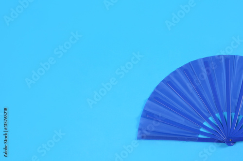 Hand fan on light blue background  top view. Space for text