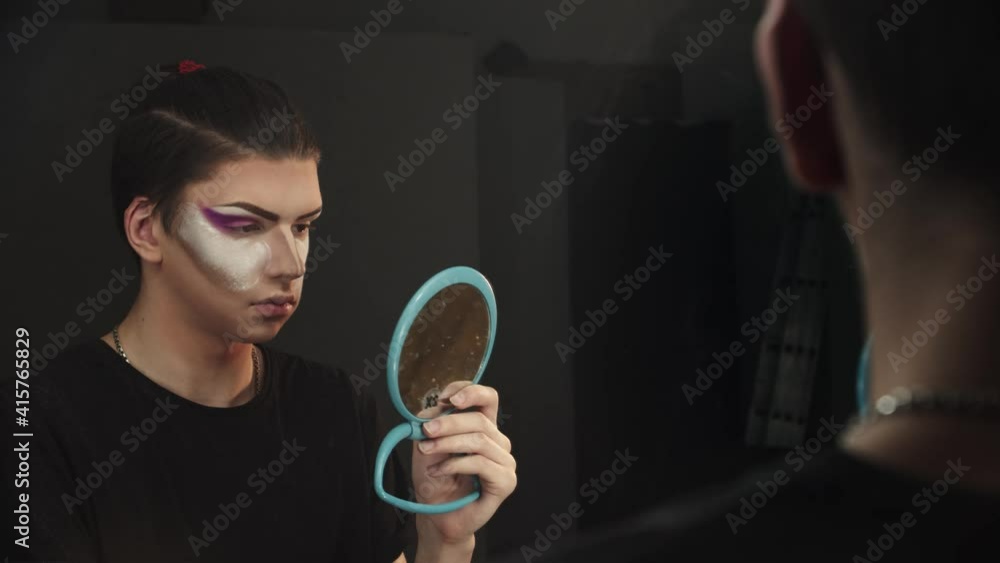 Drag artist - young man applying baking powder under his eyes Drag artist - young man applying baking powder under his eyes