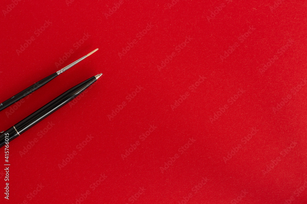 Black pen, pencil and brush on red background Black pen, pencil and brush on red background