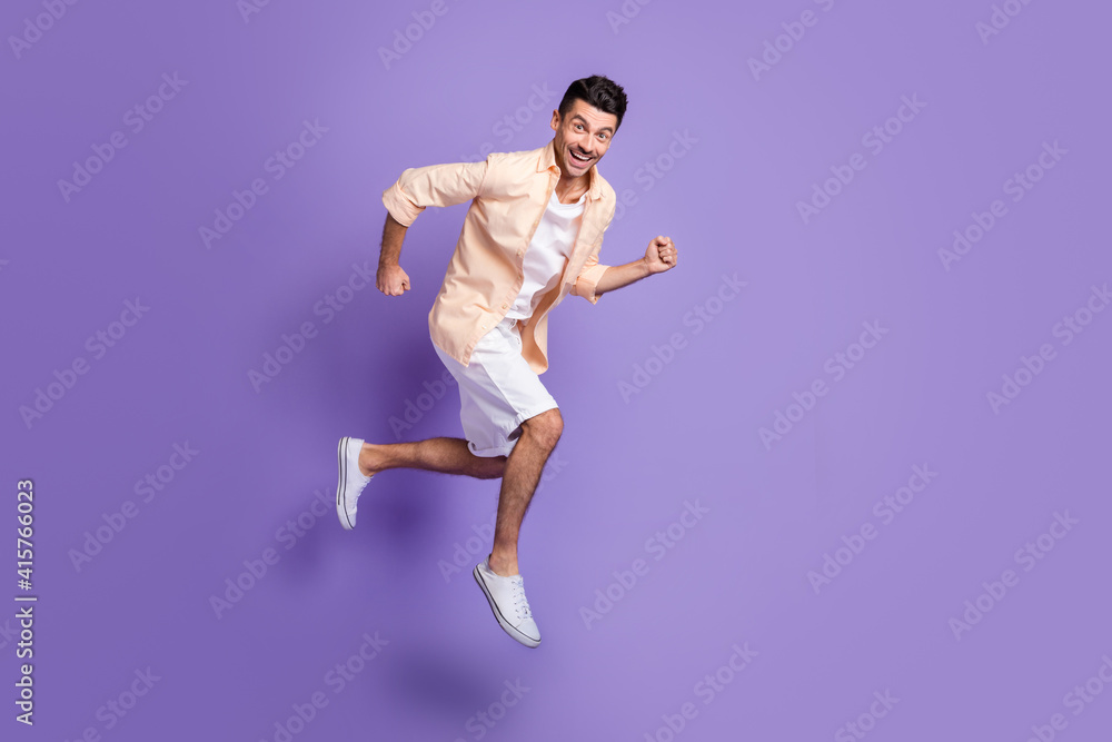 Full size profile photo of hooray brunet guy jump run wear peach shirt shorts sneakers isolated on lilac background Full size profile photo of hooray brunet guy jump run wear peach shirt shorts sneakers isolated on lilac background