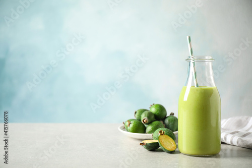 Fresh feijoa smoothie and fresh fruits on grey table, space for text