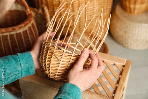 Man weaving wicker basket indoors, closeup view