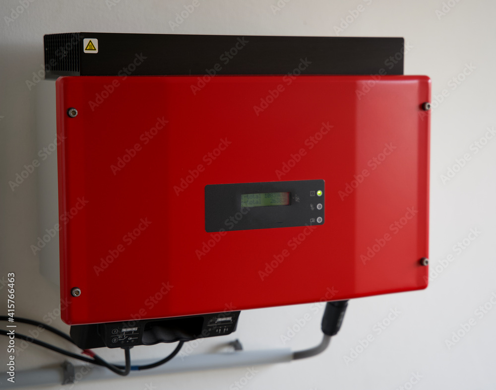 red solar power inverter mounted on a white wall. Omvormer for solar energy. Transforming to 230V power grid.