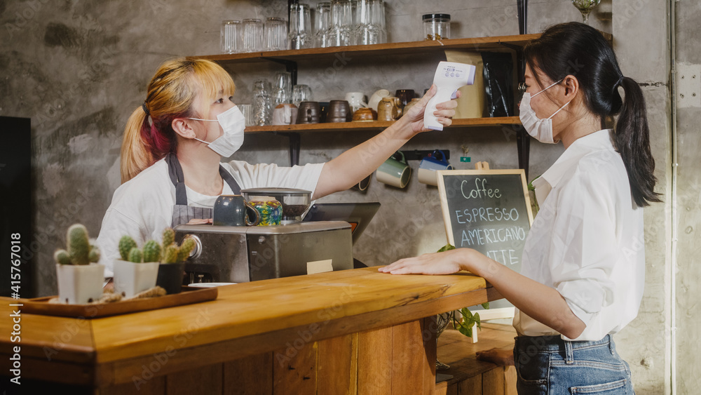 Young Asia female restaurant staff wearing protective face mask using ...