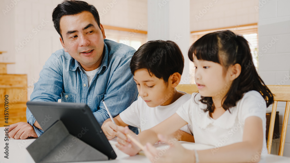 Happy Asia family homeschooling, father teach children using digital tablet in living room at home. Spending time together, Self-isolation, Social distancing, Quarantine for corona virus prevention. Happy Asia family homeschooling, father teach children using digital tablet in living room at home. Spending time together, Self-isolation, Social distancing, Quarantine for corona virus prevention.