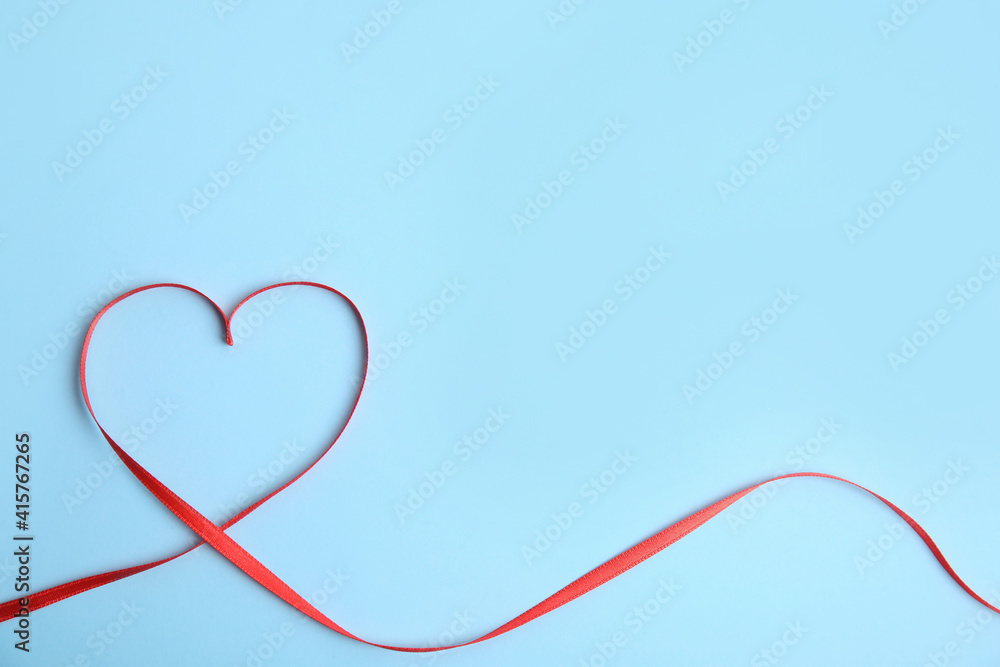 Heart made of red ribbon on light blue background, top view with space for text. Valentine's day celebration