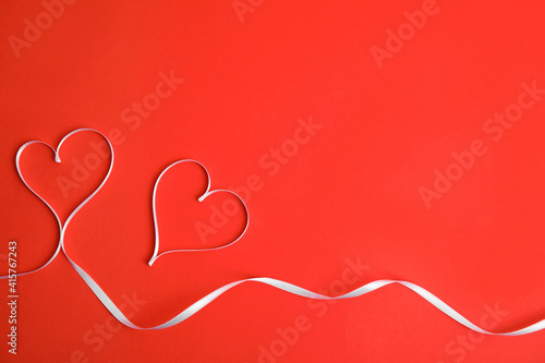 Hearts made of white ribbon on red background, flat lay with space for text. Valentine's day celebration