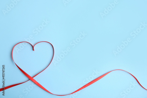 Heart made of red ribbon on light blue background, top view with space for text. Valentine's day celebration