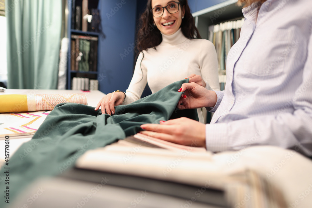 Obraz premium Woman designer showing client green fabric in curtains salon