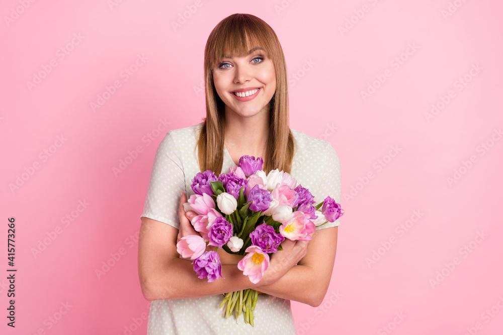Portrait of pretty cheerful girl holding in hands hugging bunch flowers congrats festal event isolated over pink pastel color background Portrait of pretty cheerful girl holding in hands hugging bunch flowers congrats festal event isolated over pink pastel color background